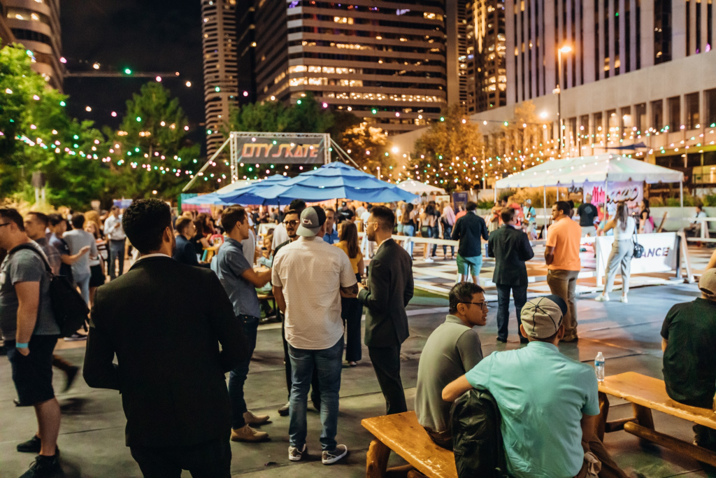 A crowd of Colorado Startup Week attendees standing and sitting in a courtyard, talking to each other.