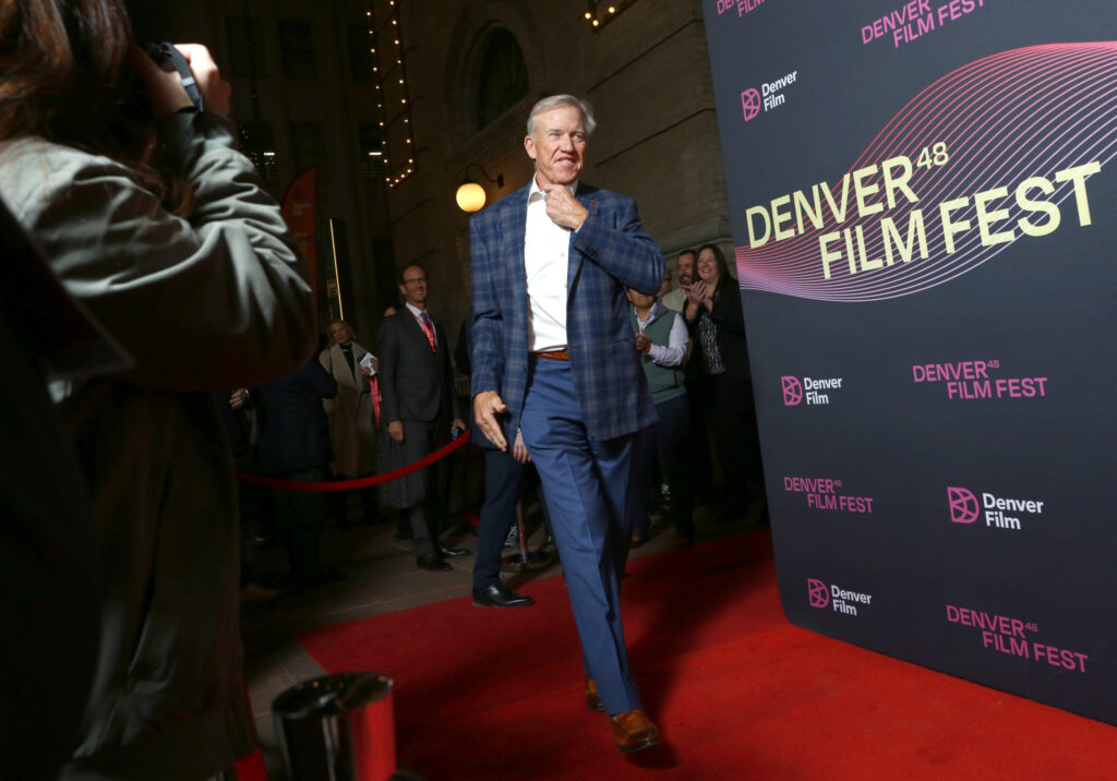 Former Denver Broncos quarterback John Elway walks the red carpet at the 48th Denver Film Festival premiere of the Netflix documentary Elway, greeting fans and photographers with a smile.
