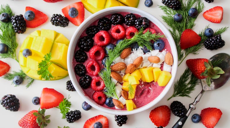 A vibrant, healthy fruit smoothie bowl topped with fresh berries, mango, and almonds.