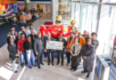 Group photo inside MSU Denver’s atrium shows fraternity members, university leaders and students gathered around a large ceremonial $17,000 check in front of oversized red “MSU” letters and black-and-gold balloon décor.