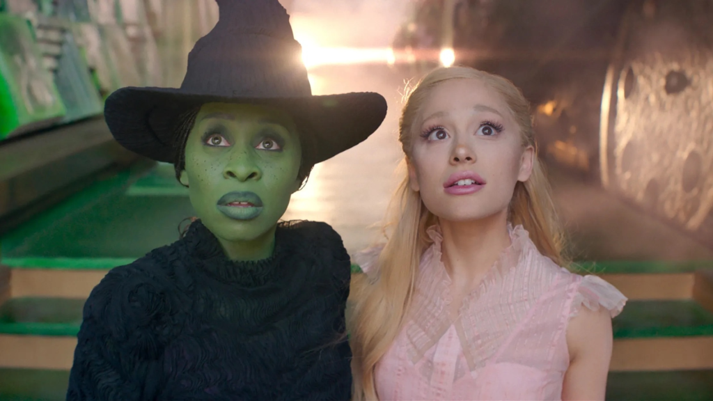Cynthia Erivo as Elphaba alongside Ariana Grande as Glinda in a scene from Wicked, both looking upward with expressive reactions.