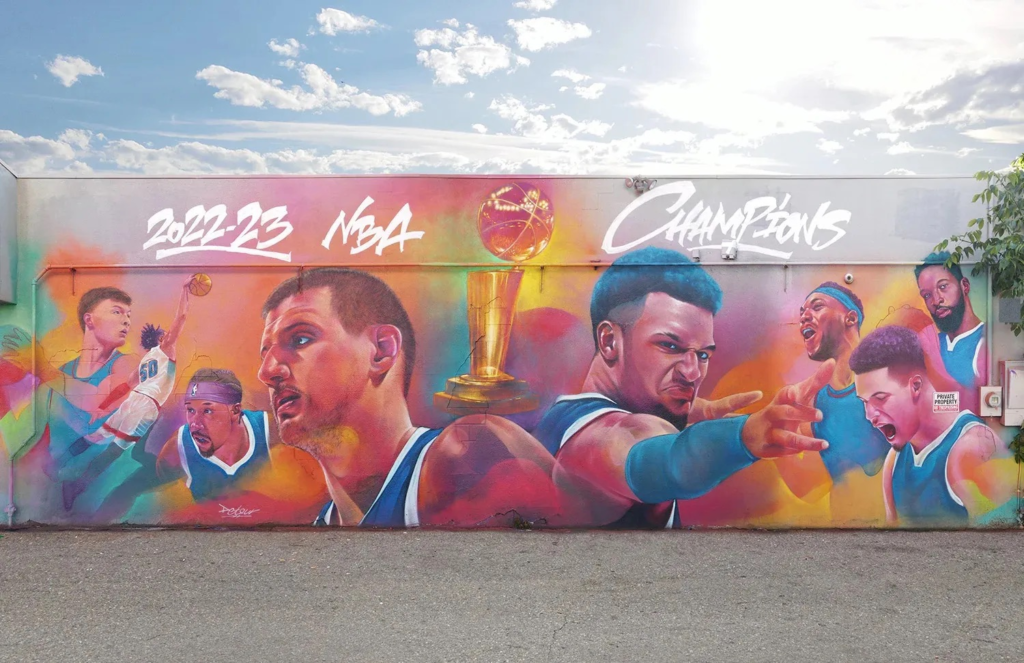 Large outdoor mural celebrating the 2022–23 NBA champion Denver Nuggets, featuring painted portraits of players and a championship trophy.
