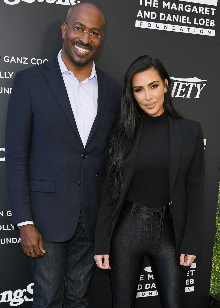 A man and a woman pose together on a red carpet in front of a step-and-repeat backdrop at a formal event.