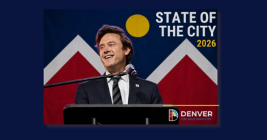 Denver Mayor Mike Johnston smiles while delivering the 2026 State of the City address from a podium, with the Denver city flag displayed behind him and the words "2026 State of the City" featured prominently on the graphic.