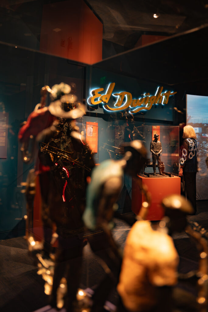 Visitors view sculptures in the "Ed Dwight: Casting a Legacy" exhibition at History Colorado Center, with artwork displayed throughout the gallery.
