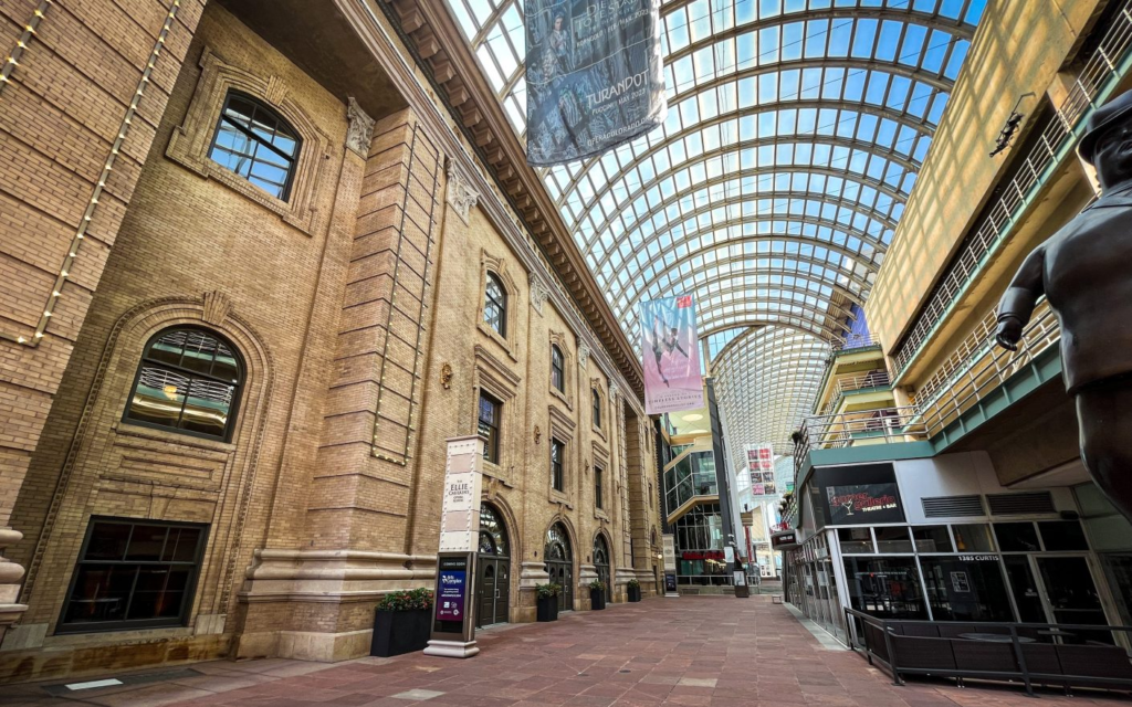 The Denver Performing Arts Complex’s covered Galleria walkway, with the Ellie Caulkins Opera House and Garner Galleria Theatre visible beneath the glass canopy.