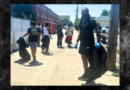 Volunteers wearing gloves carry trash bags while cleaning an alley in Denver’s East Colfax neighborhood as part of a community service project.