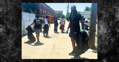 Volunteers wearing gloves carry trash bags while cleaning an alley in Denver’s East Colfax neighborhood as part of a community service project.