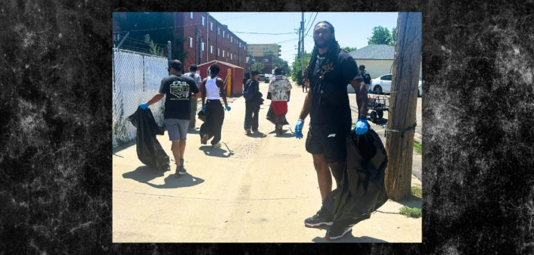 Volunteers wearing gloves carry trash bags while cleaning an alley in Denver’s East Colfax neighborhood as part of a community service project.