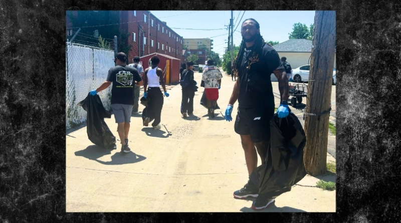 Volunteers wearing gloves carry trash bags while cleaning an alley in Denver’s East Colfax neighborhood as part of a community service project.