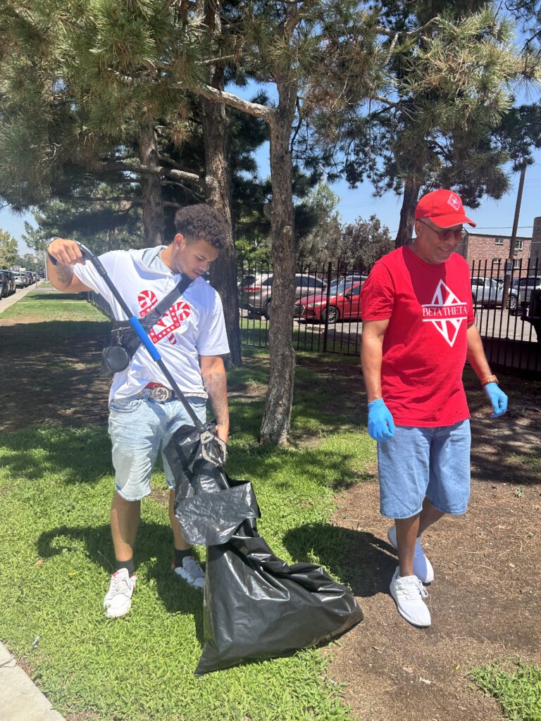 Two Beta Theta Achievement Foundation volunteers collect trash outdoors during a community cleanup in Denver’s East Colfax neighborhood.