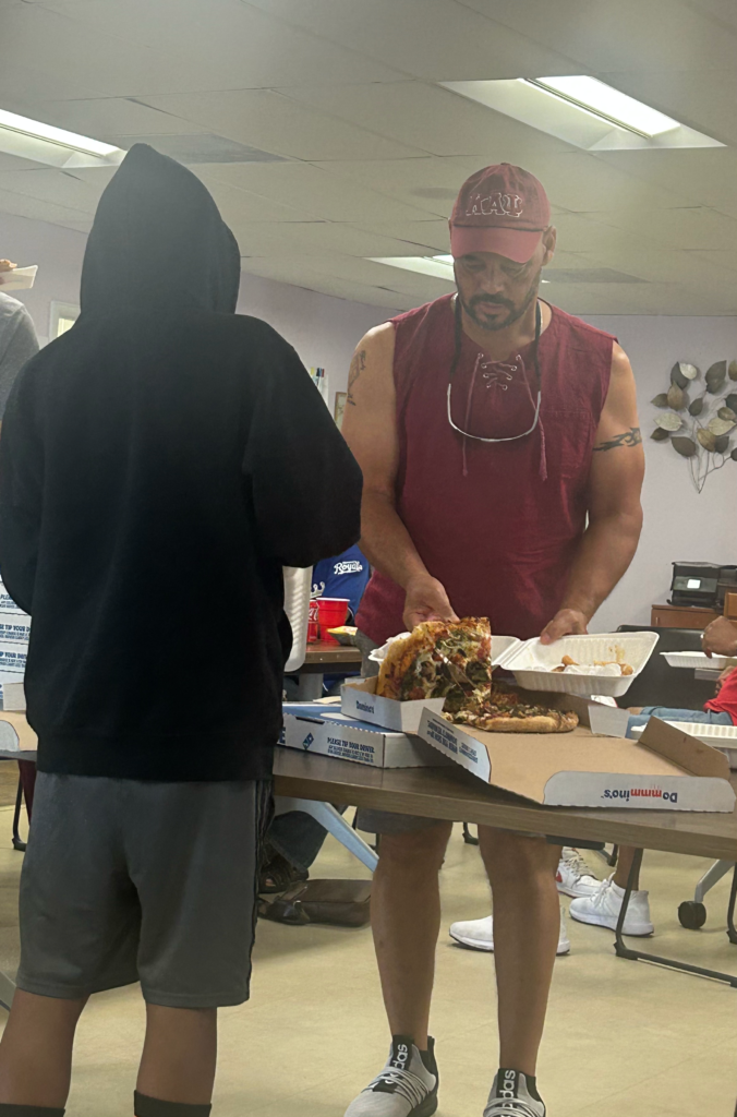 A Beta Theta Achievement Foundation member serves pizza to a young participant during a gathering at Street Fraternity in Denver.