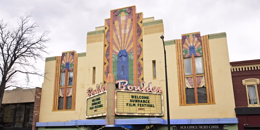 Art Deco façade of the Boulder Theater beneath an overcast sky, with its marquee reading, “Welcome Sundance Film Festival 2027.”