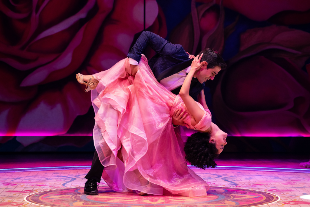 Adrián Javier dips Victoria Gómez during a romantic dance scene in Destiny of Desire against a vivid rose backdrop.