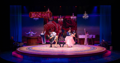 The cast of Destiny of Desire performs an energetic casino scene against a rose-covered backdrop with dramatic lighting and chandeliers.