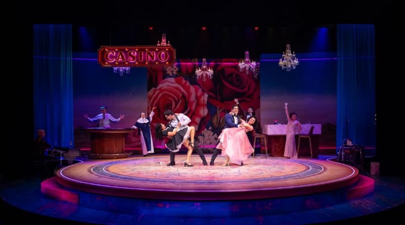 The cast of Destiny of Desire performs an energetic casino scene against a rose-covered backdrop with dramatic lighting and chandeliers.
