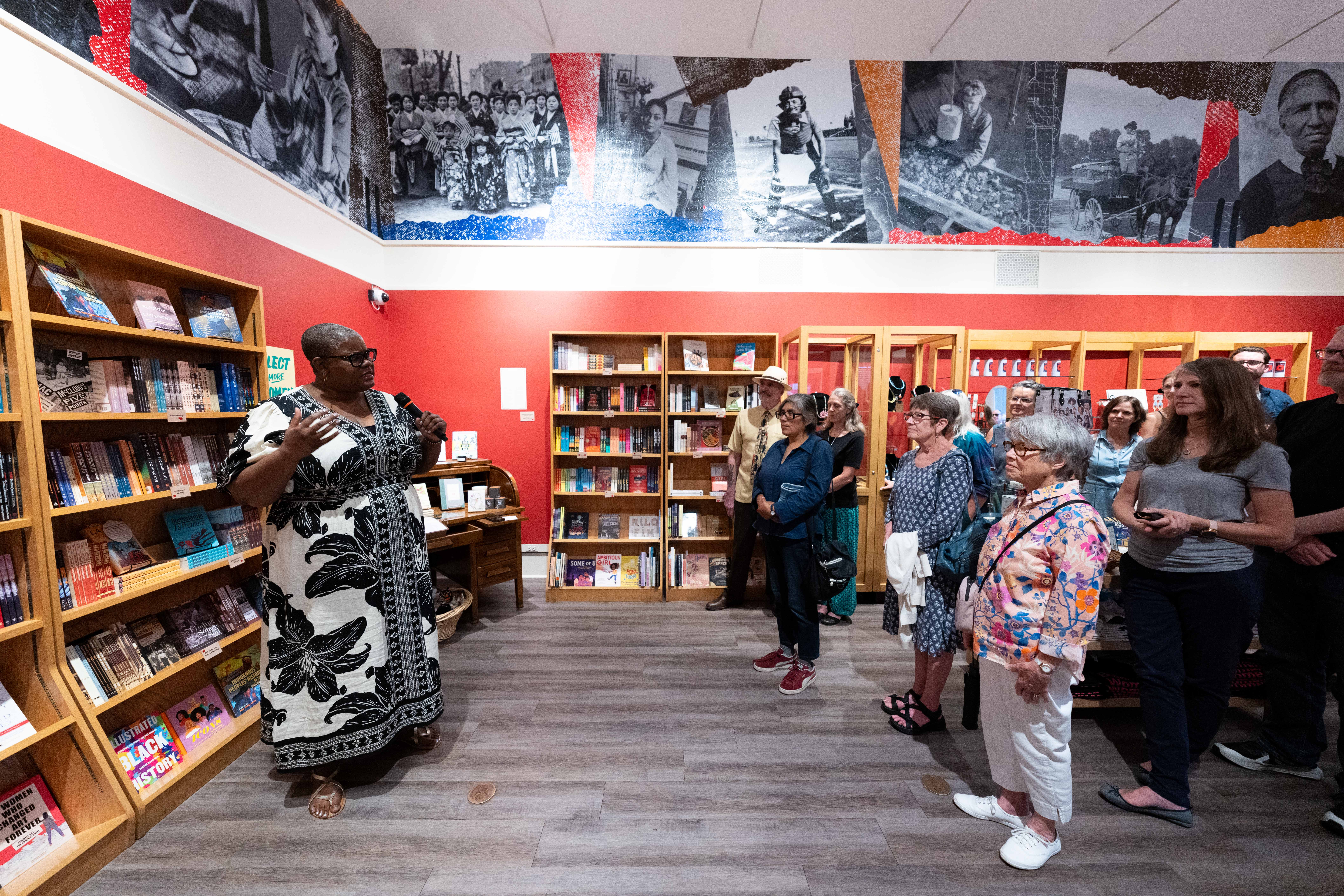 A woman addresses visitors gathered beneath the Shared History mural during an artist talk at the Center for Colorado Women’s History.