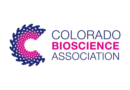 Colorado BioScience Association logo featuring a circular woven design in navy blue and magenta beside the organization's name in matching colors on a white background.